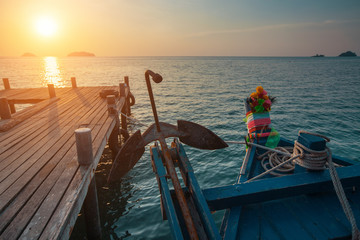 Wooden fishing boat near the pier during sunset.