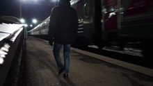 Young Man Is Waiting For The Train And Walking Along The Platform At Night. 

