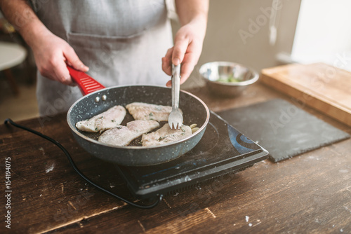 Fotomural Chef cooking sea bass fish fillet on a frying pan