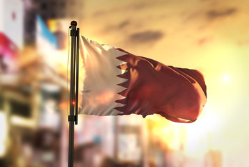 Sticker - Qatar Flag Against City Blurred Background At Sunrise Backlight