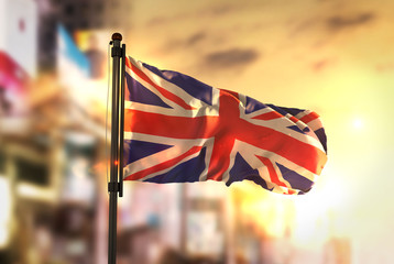 Wall Mural - United Kingdom Flag Against City Blurred Background At Sunrise Backlight