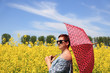 Kobieta z parasolem na tle kwitnącego rzepaku.