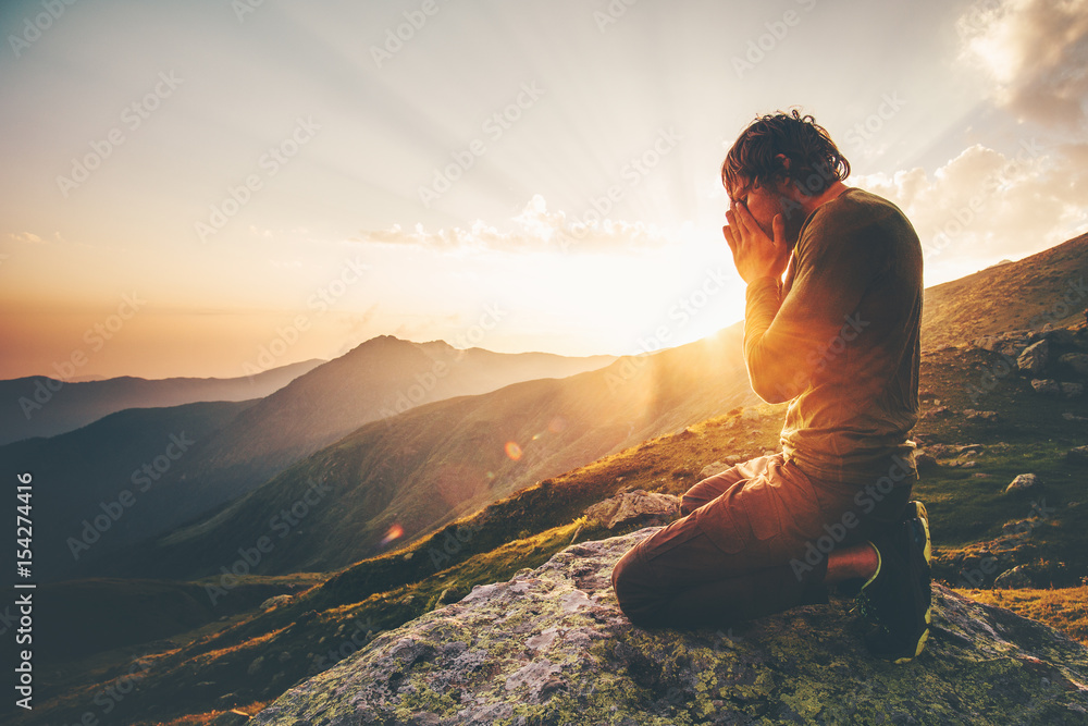 Man praying at sunset mountains Travel Lifestyle spiritual relaxation emotional meditating concept vacations outdoor harmony with nature landscape - obrazy, fototapety, plakaty 