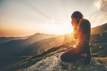 Man praying at sunset mountains Travel Lifestyle spiritual relaxation emotional meditating concept vacations outdoor harmony with nature landscape