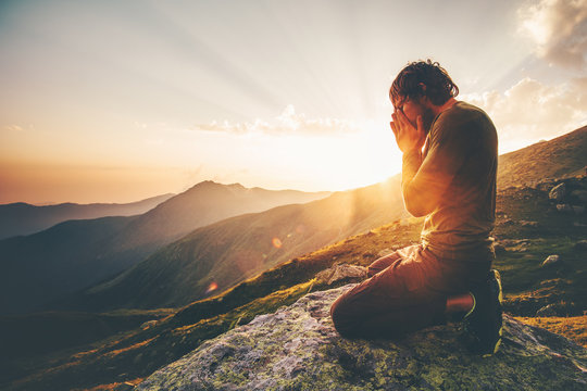 man praying at sunset mountains travel lifestyle spiritual relaxation emotional meditating concept v
