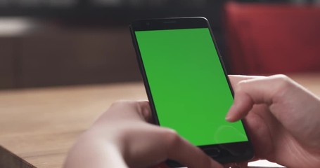 Wall Mural - Slide shot of female teen girl using smartphone with green screen sitting at the table, 4k 60fps prores footage