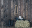 A cowboy hat, boots and a guitar on the background of an old barn.
