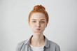 Funny pretty girl puffing out her cheeks against studio wall background. Headshot of charming red haired young woman making mouths while having fun indoors. People, lifestyle, youth and happiness