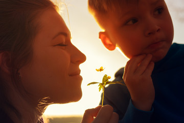 Wall Mural - Happy smiling mother and child smelling flower