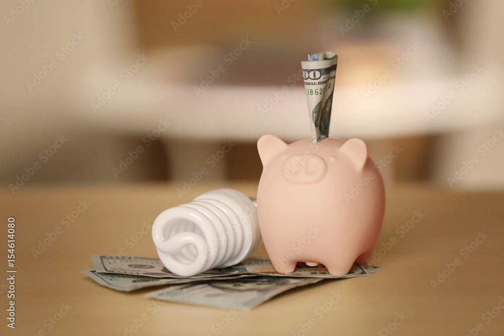 Saving electric power concept. Ceramic piggy bank with money on table