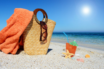 Straw bag, beach towel and cocktail