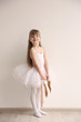 © Africa Studio - Beautiful little ballerina holding ballet shoes in light dance studio