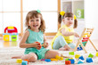 Children toddler and preschooler girls play logical toy learning shapes, arithmetic and colors in kindergarten or nursery