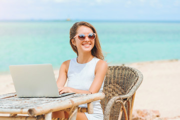 Young sexy woman using laptop on the beach. Freelance work