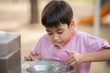 Little asian boy drinking water in the public park