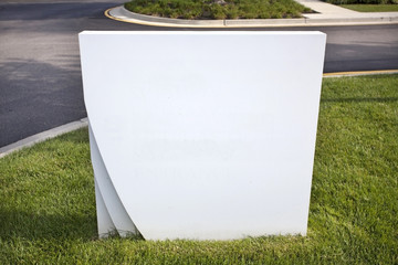 Wall Mural - Close up of blank white sign embedded in grass under blue sky. Copy space. 
