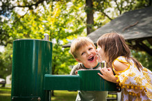 Two Children Drinking From A Water Fountain