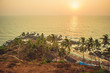 Palm trees in the rays of the sunset in the background rocks and the Arabian Sea