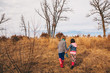 © RooM The Agency - Boy and girl holding hands running in rural landscape