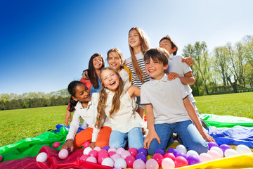 Wall Mural - Laughing kids sitting in the center of parachute