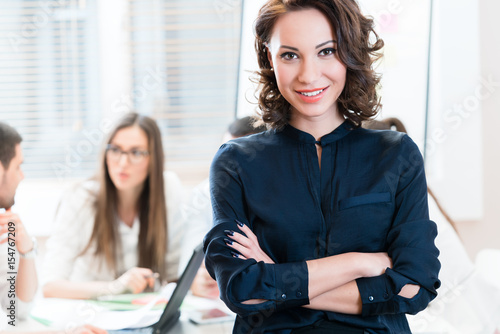 Fotografía Manager with her team working in the office looking into camera