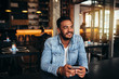 © Jacob Lund - Young man sitting in coffee shop with mobile phone