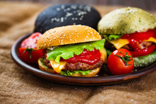Three Burgers With Different Bread Buns On Clay Dish On Rustic Wooden Table.