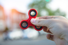 Man Playing With Fidget Spinner Stress Relieving Toy Outdoors On City Street.