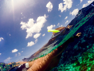 Wall Mural - Guy diving in beautiful clear water. Over-under selfie with beautiful sky.