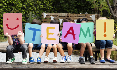 Wall Mural - Children are sitting on the wooden table holding a word team