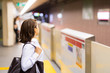© metamorworks - young woman waiting the subway on platform.