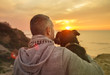 Man and his faithful dog enjoying an ocean sunset