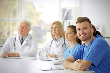 Poster - Team of doctors sitting at table in clinic