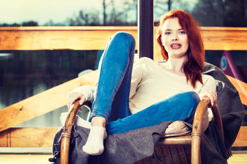 Atractive red-haired woman resting sitting on Rocking chair in f