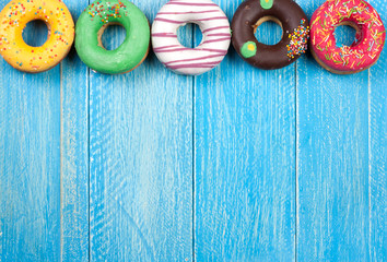 Wall Mural - glazed donuts on a blue wooden background with copy space for your text. Top view