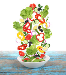 flying  salad with plate on wooden table