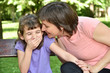 © zdravinjo - Mother whispering secret into ears of smiling daughter