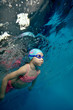 © alexbard - Sports little girl swimming underwater on a blue background in a pink swimsuit. Portrait. Close-up. Shooting under water. Vertical view