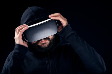 Poster - Young hipster bearded man wearing virtual reality goggles. Black background studio VR concept