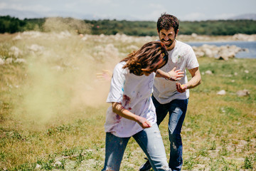 Wall Mural - Lovely couple having fun outdoors playing with colorful holi powder. Lifestyle portrait