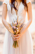 Unusual wedding bouquet in hands of bride. Bride in the rays sun.