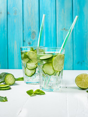 Wall Mural - Cold and refreshing infused detox water with lime, mint and cucumber in a glass on wood background