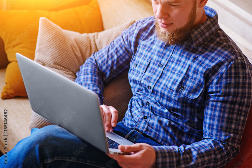 Young man working with computer on the beach. Handsome man working with laptop laying on the couch at the beach