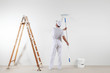 © amedeoemaja - Rear view of painter man looking at blank wall, with paint stick roller, bucket and wooden ladder, isolated on white room