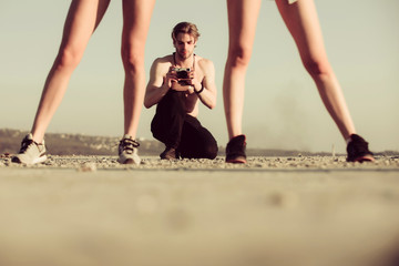 Canvas Print - Muscular man, photographer with camera and sexy legs of women