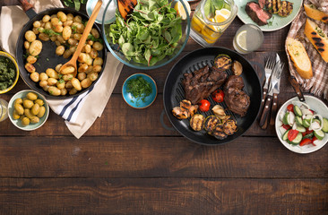 Wall Mural - Dinner table with grilled steak, vegetables, potatoes, salad, snacks, lemonade