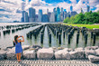 New York tourist woman taking mobile picture with smartphone. Manhattan city skyline waterfront lifestyle. People walking enjoying view of downtown from the Brooklyn bridge park Pier 1 salt marsh.