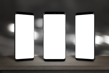 Leinwandbilder - Three mobile phones with isolated screen for mockup on the table. Bokeh lights in background.