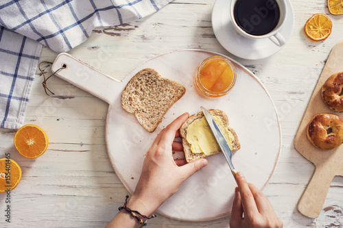 Zdjęcie XXL Kobiety ręka rozprzestrzenia masło na pokrojonym chlebie