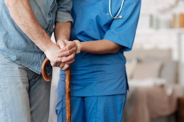 Wall Mural - Kind trained nurse helping feeble gentleman walking